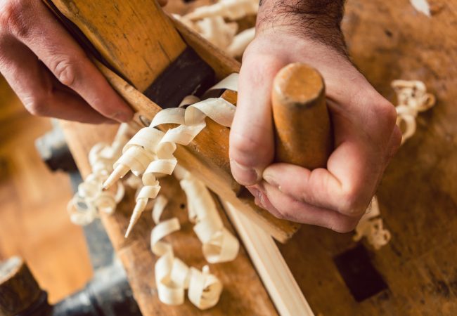 Top view on master carpenter working with wood planer, hands and tool to be seen